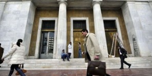 Des-personnes-passent-devant-le-siège-de-la-banque-de-Grèce-à-Athènes-le-7-mars-2012-